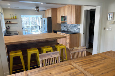 Example of a mid-sized u-shaped medium tone wood floor and brown floor eat-in kitchen design in Other with an undermount sink, shaker cabinets, medium tone wood cabinets, soapstone countertops, blue backsplash, glass tile backsplash and an island