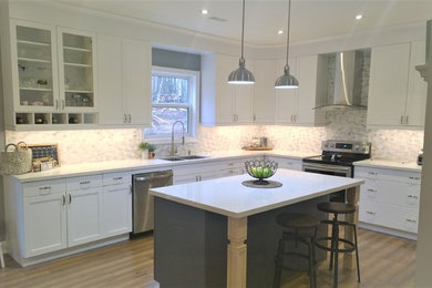 Mid-sized arts and crafts l-shaped medium tone wood floor and brown floor eat-in kitchen photo in Other with a double-bowl sink, shaker cabinets, white cabinets, quartz countertops, multicolored backsplash, ceramic backsplash, stainless steel appliances and an island