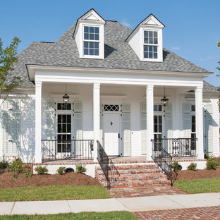 Foto på ett litet vintage vitt trähus, med två våningar och valmat tak