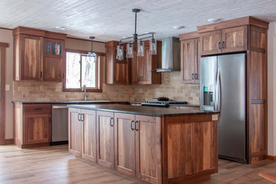 Inspiration for a l-shaped kitchen remodel in Other with a double-bowl sink, flat-panel cabinets, medium tone wood cabinets, beige backsplash, an island and black countertops