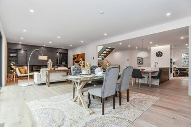 Photo of a large modern open plan dining in Toronto with white walls, light hardwood floors, no fireplace and beige floor.
