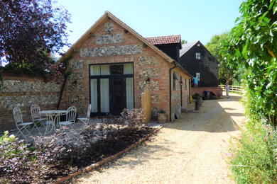Photo of a rustic two floor side detached house in Wiltshire with mixed cladding, a hip roof, a tiled roof and a red roof.