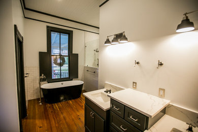 Design ideas for a large traditional ensuite bathroom in Other with recessed-panel cabinets, black cabinets, a freestanding bath, white tiles, metro tiles, white walls, medium hardwood flooring, a built-in sink, brown floors, white worktops, double sinks, a built in vanity unit and a wood ceiling.