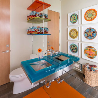 Esempio di un bagno di servizio minimalista di medie dimensioni con nessun'anta, WC monopezzo, pareti beige, pavimento in gres porcellanato, lavabo integrato, top in vetro e top blu