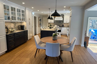 Large elegant u-shaped medium tone wood floor and brown floor eat-in kitchen photo in Boston with a farmhouse sink, raised-panel cabinets, white cabinets, marble countertops, blue backsplash, marble backsplash, white appliances, an island and blue countertops