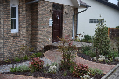 Kleiner Landhausstil Vorgarten mit Pflastersteinen in Sonstige