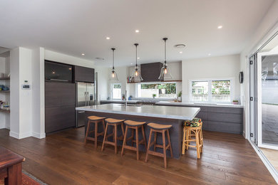 Inspiration for a large modern galley eat-in kitchen in Gold Coast - Tweed with an undermount sink, flat-panel cabinets, dark wood cabinets, quartz benchtops, window splashback, stainless steel appliances, medium hardwood floors, with island and brown floor.