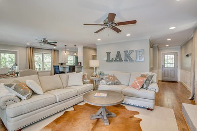 Example of a large transitional open concept medium tone wood floor and brown floor living room design in Orange County with beige walls, a standard fireplace, a brick fireplace and a tv stand