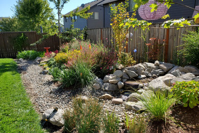 Photo of a mid-sized rustic drought-tolerant and full sun backyard river rock flower bed in Portland for summer.