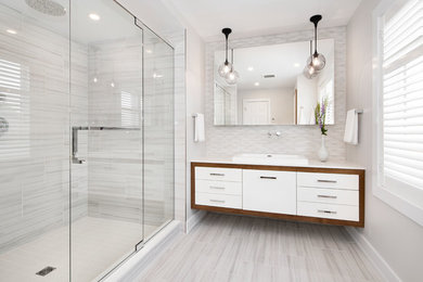 Example of a mid-sized trendy master white tile and porcelain tile porcelain tile bathroom design in Ottawa with flat-panel cabinets, white cabinets, a one-piece toilet, gray walls, a vessel sink, quartz countertops and a hinged shower door
