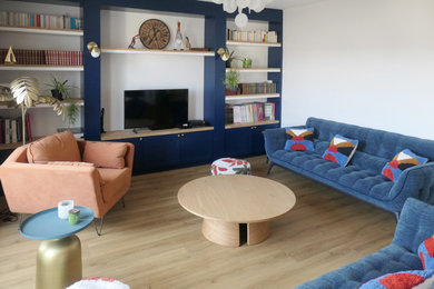 Diseño de biblioteca en casa abierta escandinava grande con paredes azules, suelo de madera clara y televisor independiente