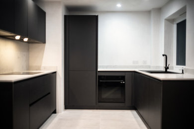 Design ideas for a small modern u-shaped kitchen/diner in Other with flat-panel cabinets, black cabinets, marble worktops, black appliances, concrete flooring, no island, grey floors and white worktops.