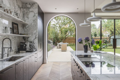 Design ideas for a contemporary galley kitchen in London with a submerged sink, flat-panel cabinets, dark wood cabinets, grey splashback, stone slab splashback, medium hardwood flooring, an island, brown floors and grey worktops.