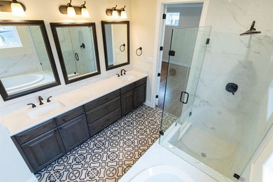 Photo of a large mediterranean master bathroom in Houston with raised-panel cabinets, grey cabinets, a drop-in tub, a corner shower, a two-piece toilet, white tile, marble, beige walls, ceramic floors, an undermount sink, marble benchtops, multi-coloured floor, a hinged shower door and white benchtops.