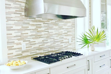 Beach style kitchen in Jacksonville with quartzite benchtops, grey splashback, glass tile splashback, stainless steel appliances, with island and white benchtop.