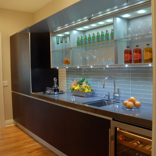 Exemple d'une grande arrière-cuisine linéaire tendance avec un évier encastré, un placard à porte persienne, des portes de placard en bois sombre, un plan de travail en quartz modifié, une crédence grise, une crédence en carreau de verre, un électroménager en acier inoxydable, un sol en bois clair, aucun îlot et un sol marron.