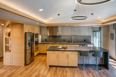 This is an example of a large modern u-shaped open plan kitchen in San Francisco with an undermount sink, flat-panel cabinets, light wood cabinets, quartz benchtops, grey splashback, stone slab splashback, stainless steel appliances, vinyl floors, with island, brown floor, grey benchtop and vaulted.