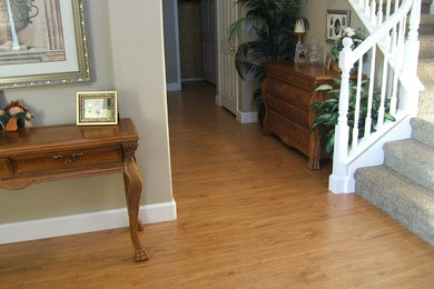This is an example of a mid-sized traditional hallway in Los Angeles with grey walls, light hardwood floors and brown floor.