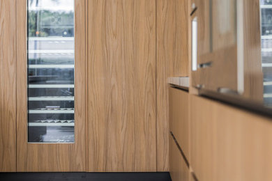 Foto de cocina moderna grande con armarios con paneles lisos, puertas de armario de madera clara, encimera de acrílico y una isla