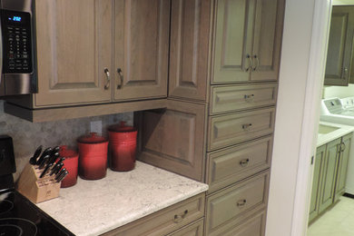 Mid-sized elegant ceramic tile and beige floor enclosed kitchen photo in Miami with raised-panel cabinets, brown cabinets, gray backsplash, stone tile backsplash and black appliances