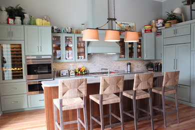 Mid-sized transitional l-shaped light wood floor and beige floor eat-in kitchen photo in Philadelphia with an undermount sink, shaker cabinets, green cabinets, granite countertops, beige backsplash, ceramic backsplash, stainless steel appliances and an island
