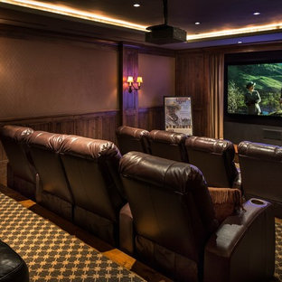 This is an example of a large rustic enclosed home cinema in Santa Barbara with brown walls, carpet and a projector screen.