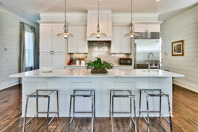 Inspiration for a mid-sized beach style galley open plan kitchen in Miami with shaker cabinets, white cabinets, marble benchtops, stainless steel appliances, with island, an undermount sink and medium hardwood floors.