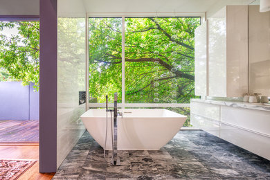 Large trendy master white tile and ceramic tile marble floor and gray floor bathroom photo in Toronto with flat-panel cabinets, white cabinets, a one-piece toilet, white walls, an undermount sink, marble countertops and a hinged shower door