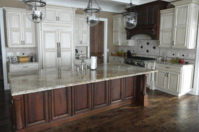 Kitchen - traditional medium tone wood floor kitchen idea in Other with an undermount sink, raised-panel cabinets, distressed cabinets, granite countertops, porcelain backsplash and stainless steel appliances