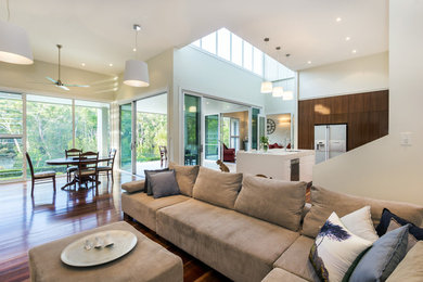 This is an example of an expansive contemporary formal open concept living room in Sydney with medium hardwood floors, white walls and no fireplace.