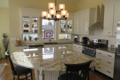 Open concept kitchen - transitional l-shaped medium tone wood floor open concept kitchen idea in Grand Rapids with an undermount sink, raised-panel cabinets, white cabinets, granite countertops, white backsplash, stainless steel appliances and an island