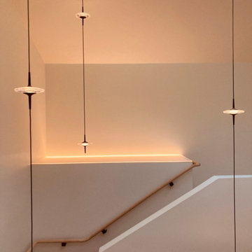 Pendants above stair and under skylight with glowing panel in the evening.