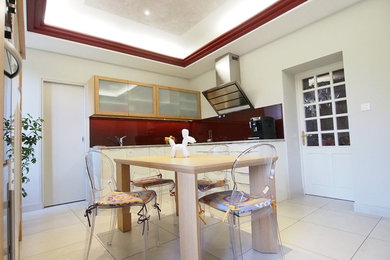 Mid-sized contemporary l-shaped eat-in kitchen in Toulouse with an undermount sink, white cabinets, granite benchtops, red splashback, glass sheet splashback, stainless steel appliances, ceramic floors and no island.