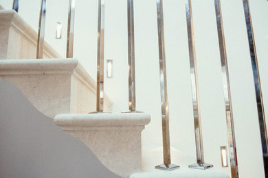 Diseño de escalera en U clásica con escalones de piedra caliza, contrahuellas de piedra caliza y barandilla de metal
