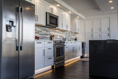 Inspiration for a transitional dark wood floor and brown floor kitchen remodel in Chicago with white cabinets, granite countertops, gray backsplash, an island and gray countertops