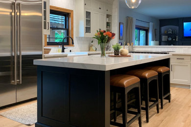 Example of a mid-sized classic l-shaped light wood floor kitchen design in Milwaukee with quartz countertops, white backsplash and an island