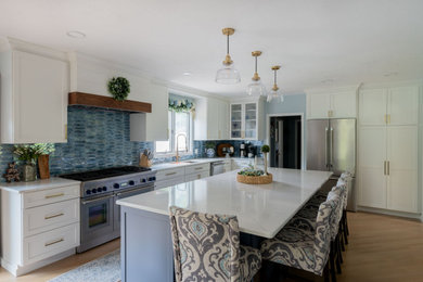 Inspiration for a large transitional l-shaped light wood floor and brown floor eat-in kitchen remodel in Boston with an undermount sink, shaker cabinets, white cabinets, quartz countertops, blue backsplash, glass tile backsplash, stainless steel appliances, an island and white countertops
