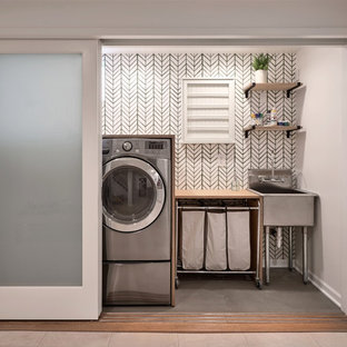 シアトルの中サイズのトランジショナルスタイルのおしゃれなランドリークローゼット (スロップシンク、木材カウンター、コンクリートの床、左右配置の洗濯機・乾燥機、緑の床、グレーの壁) の写真