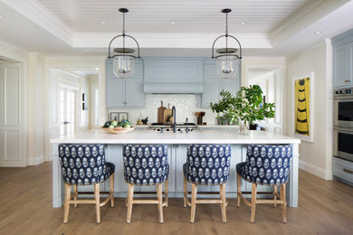 Inspiration for a mid-sized coastal medium tone wood floor, brown floor and shiplap ceiling kitchen pantry remodel in San Francisco with a farmhouse sink, recessed-panel cabinets, blue cabinets, quartzite countertops, white backsplash, ceramic backsplash, stainless steel appliances, an island and white countertops