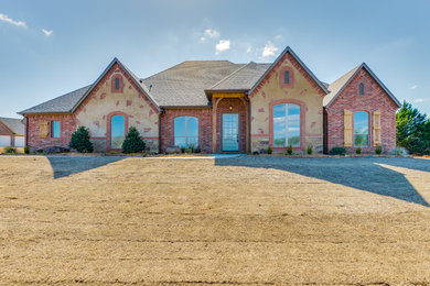 Example of a large classic red one-story brick gable roof design in Oklahoma City