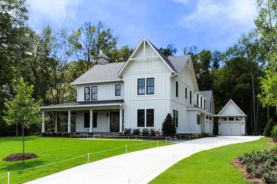 Photo of a large country two-storey white exterior in Raleigh with wood siding, a gable roof and board and batten siding.