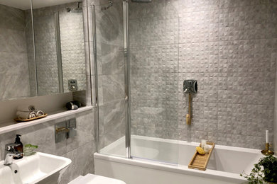 ロンドンにある北欧スタイルのおしゃれな浴室 (ドロップイン型浴槽、グレーの壁、開き戸のシャワー) の写真