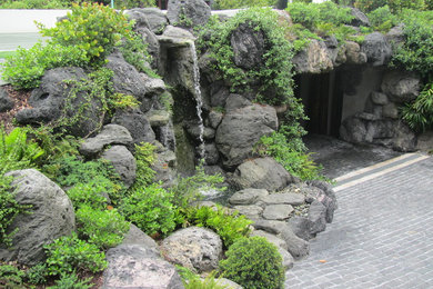 Photo of a mid-sized asian full sun front yard stone water fountain landscape in Miami.