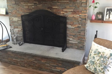 Inspiration for a large timeless enclosed porcelain tile and brown floor family room remodel in New York with a standard fireplace, a stone fireplace and a wall-mounted tv