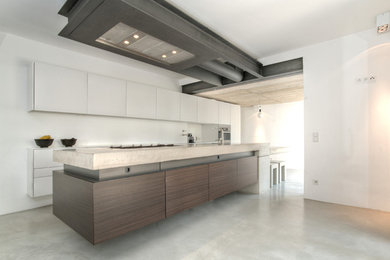 This is an example of an expansive contemporary kitchen in Cologne with an undermount sink, flat-panel cabinets, dark wood cabinets, concrete benchtops, white splashback, stainless steel appliances, concrete floors, with island, grey floor and grey benchtop.