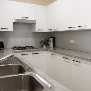 Inspiration for a small modern u-shaped kitchen pantry in Melbourne with a double-bowl sink, open cabinets, white cabinets, laminate benchtops, grey splashback, glass sheet splashback, stainless steel appliances, light hardwood floors, no island and grey benchtop.
