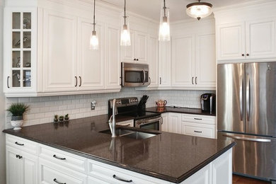 Example of a mid-sized classic u-shaped dark wood floor and brown floor eat-in kitchen design in Toronto with an undermount sink, raised-panel cabinets, white cabinets, quartz countertops, stainless steel appliances, a peninsula, white backsplash and ceramic backsplash