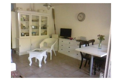 Imagen de sala de estar abierta costera pequeña sin chimenea con paredes blancas y televisor independiente