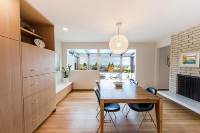 Kitchen/dining room combo - mid-sized 1960s light wood floor and brown floor kitchen/dining room combo idea in Seattle with white walls, a two-sided fireplace and a brick fireplace