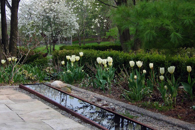 This is an example of a traditional garden in Toronto with a water feature and natural stone pavers.